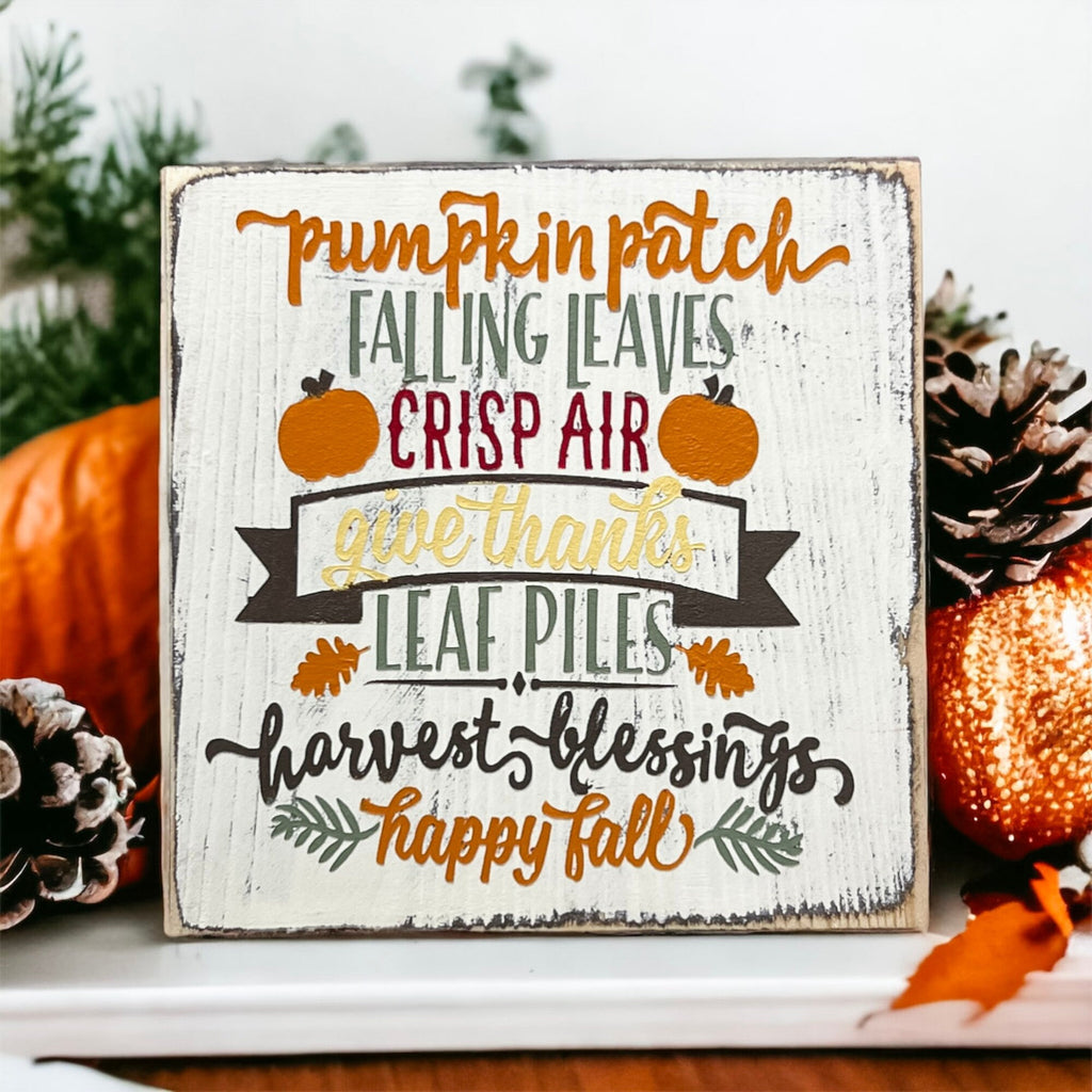 Fall sign on mantle with candles and pine cones in warm holiday setting