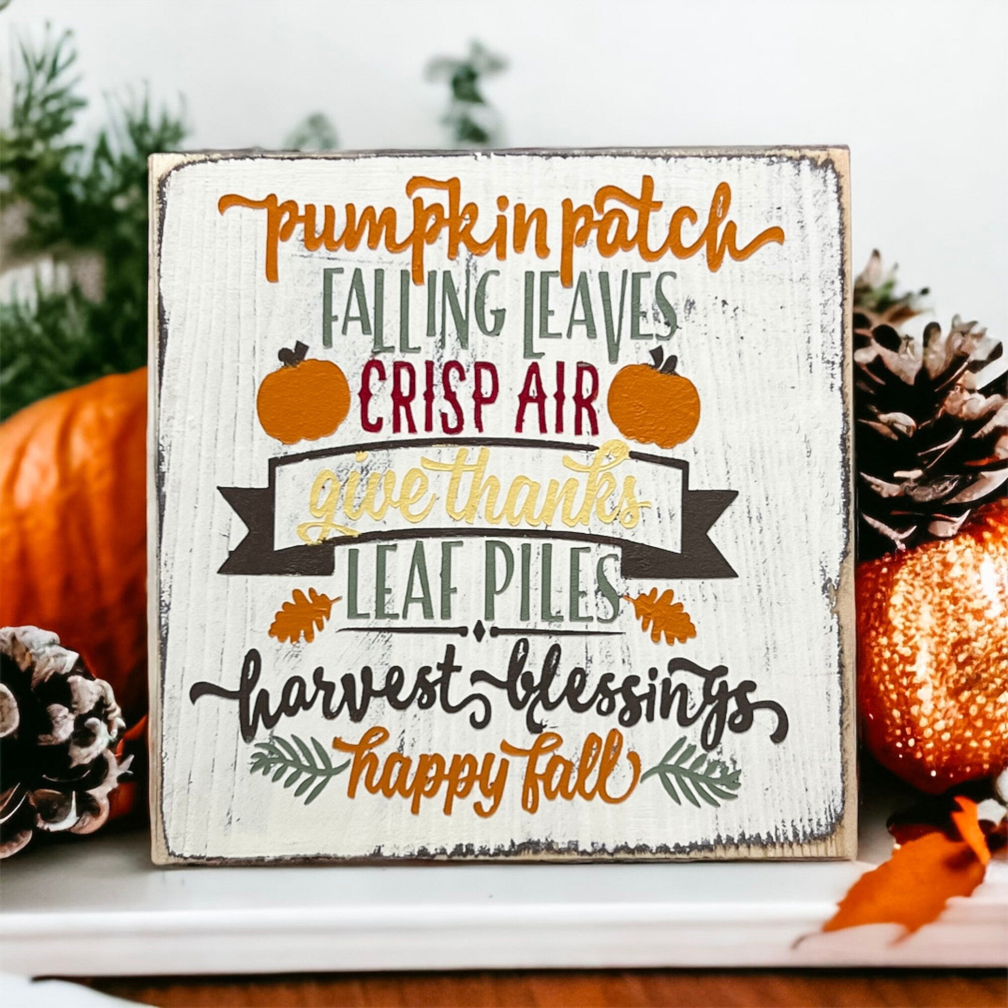 Fall sign on mantle with candles and pine cones in warm holiday setting