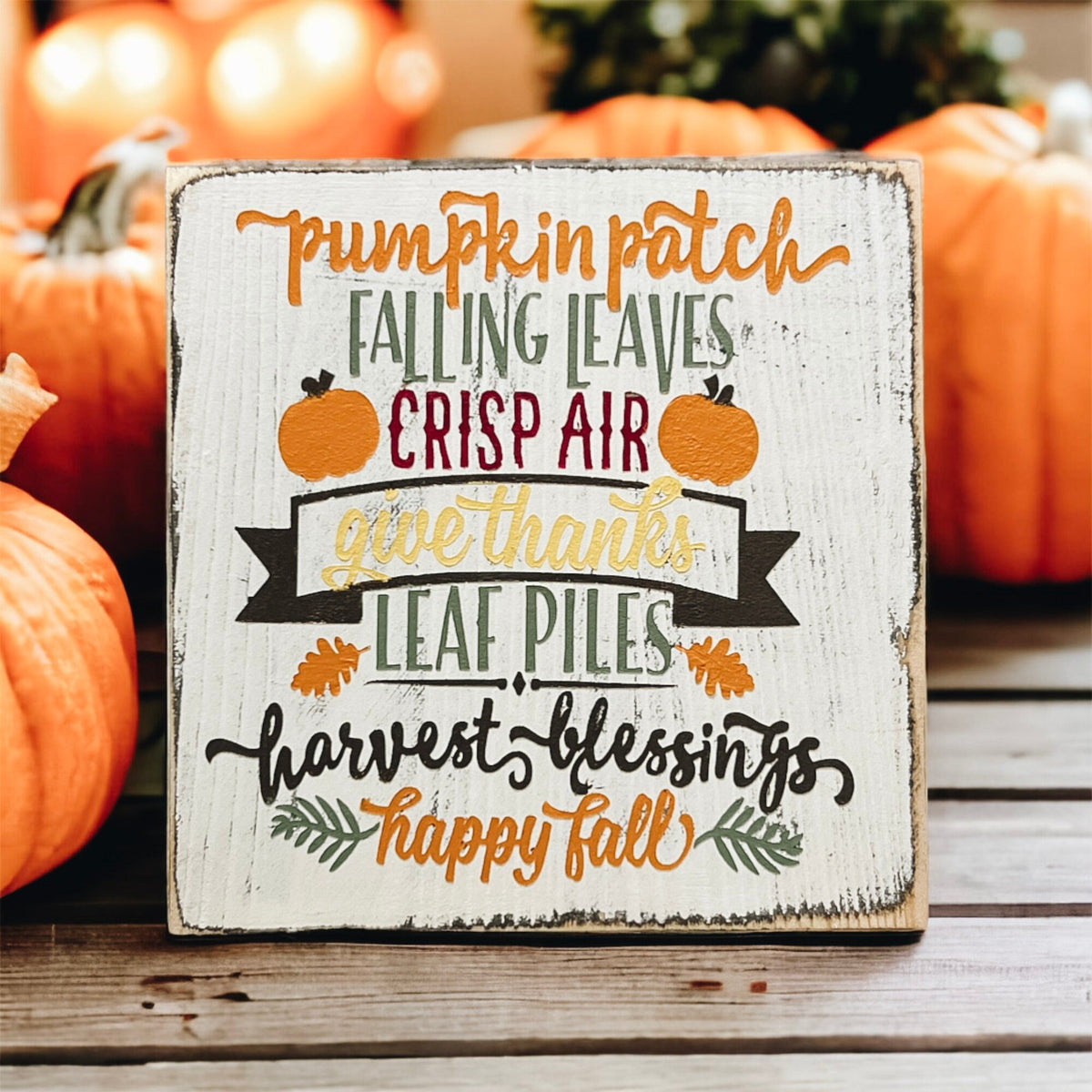 Fall sign front view on wood surface with orange pumpkins in background