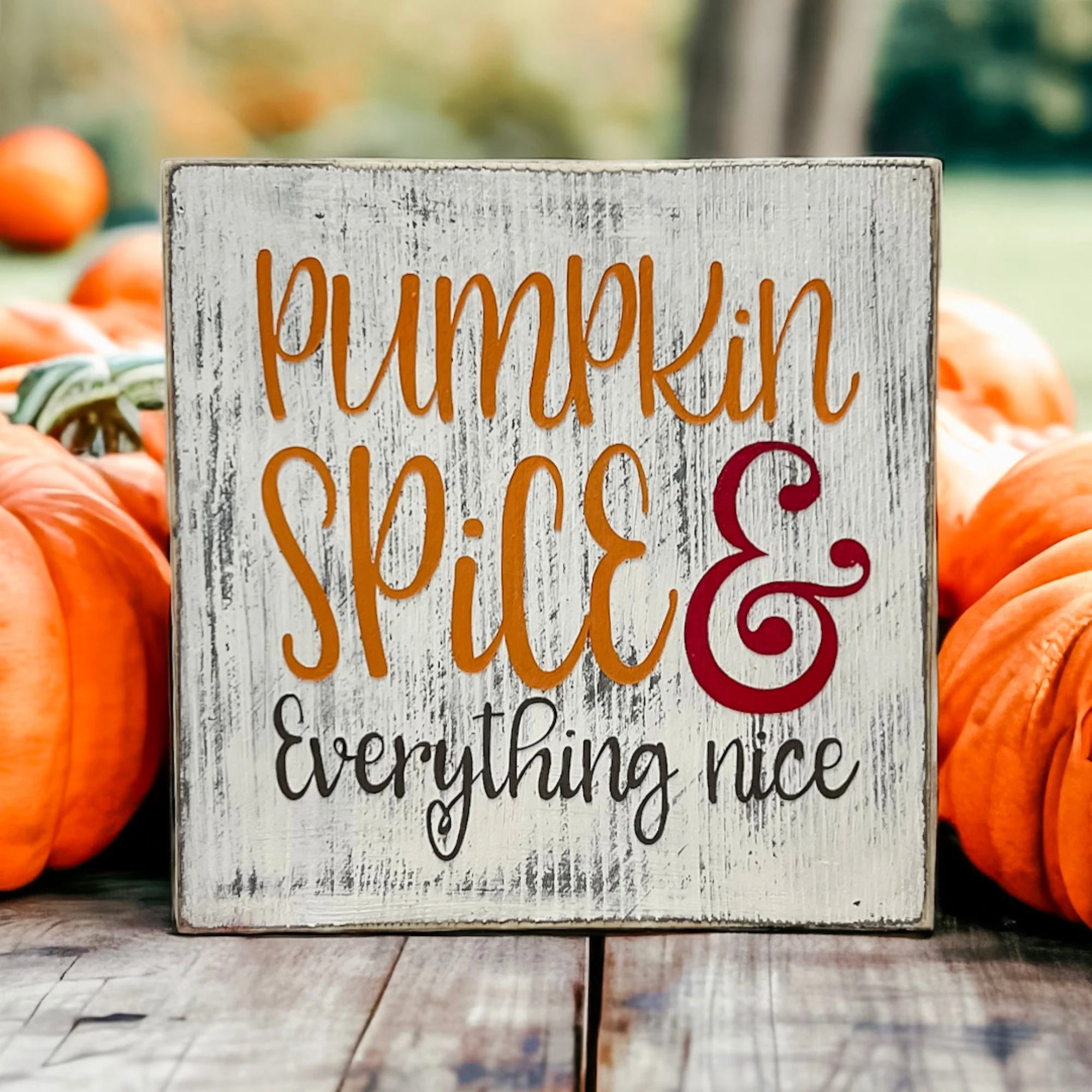Pumpkin Spice and Everything Nice distressed whitewash wood block sign with amber script orange serif and burgundy ampersand on copper tray with orange and white pumpkins and greenery