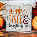 Pumpkin Spice and Everything Nice distressed whitewash wood block sign with amber script orange serif and burgundy ampersand on rustic wood surface with orange pumpkins and latte hero shot