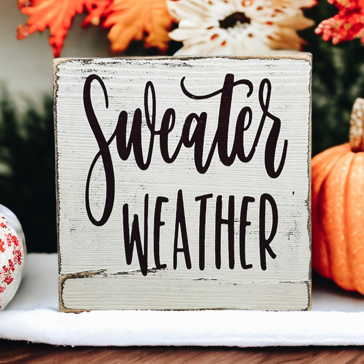 Sweater Weather sign styled with fall leaves and pumpkins