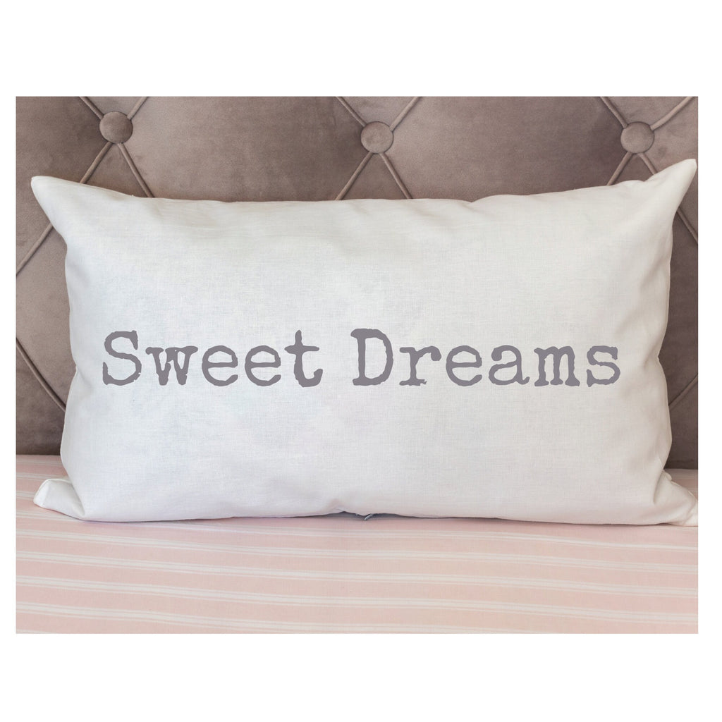 Sweet Dreams white lumbar pillow with gray distressed typewriter lettering on white knit throw blanket in wicker basket lifestyle shot close up