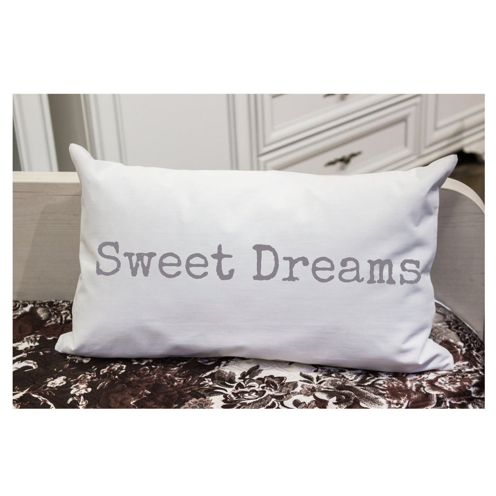 Sweet Dreams white lumbar pillow with gray distressed typewriter lettering on white distressed wood chair with sheer curtain window light lifestyle shot