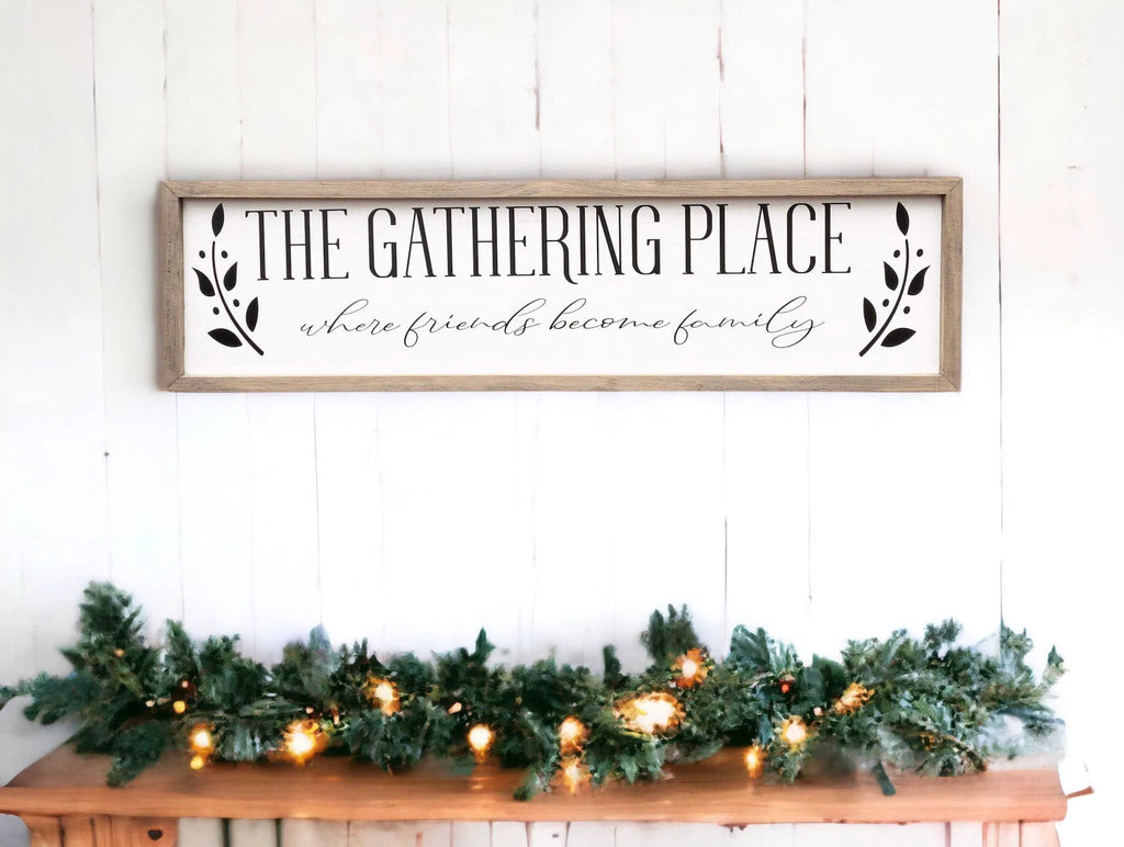 The Gathering Place where friends become family framed farmhouse sign on white shiplap wall above wood bench with white flower arrangement
