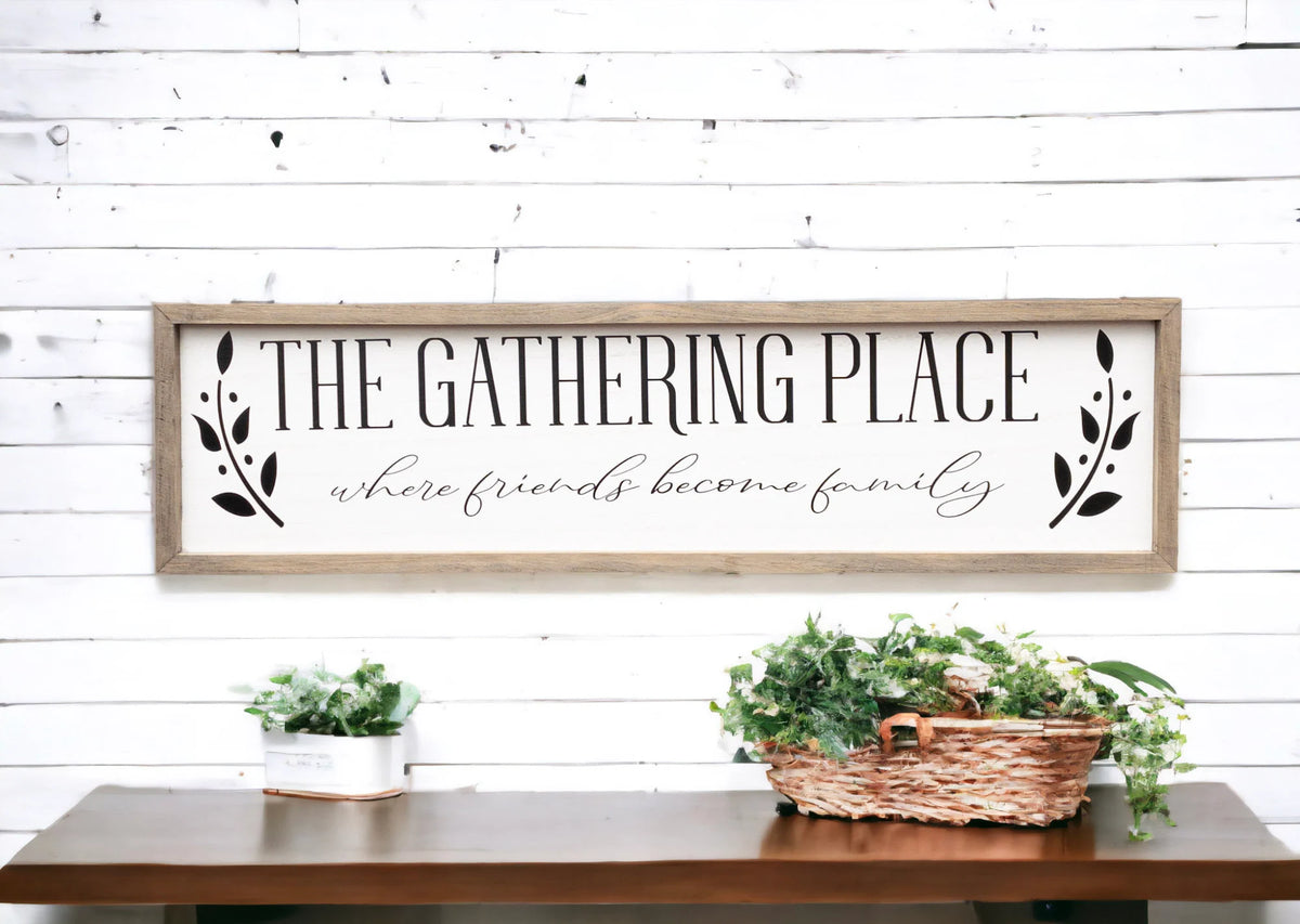 The Gathering Place where friends become family framed farmhouse sign above fall mantel with orange white and blush pumpkins and pine garland