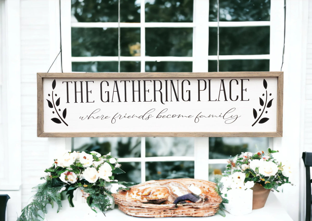 The Gathering Place where friends become family framed farmhouse sign on white shiplap wall above wood bench with white flower vase
