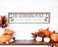The Gathering Place where friends become family framed farmhouse sign on white tile wall above kitchen counter with wicker baskets and fresh greens
