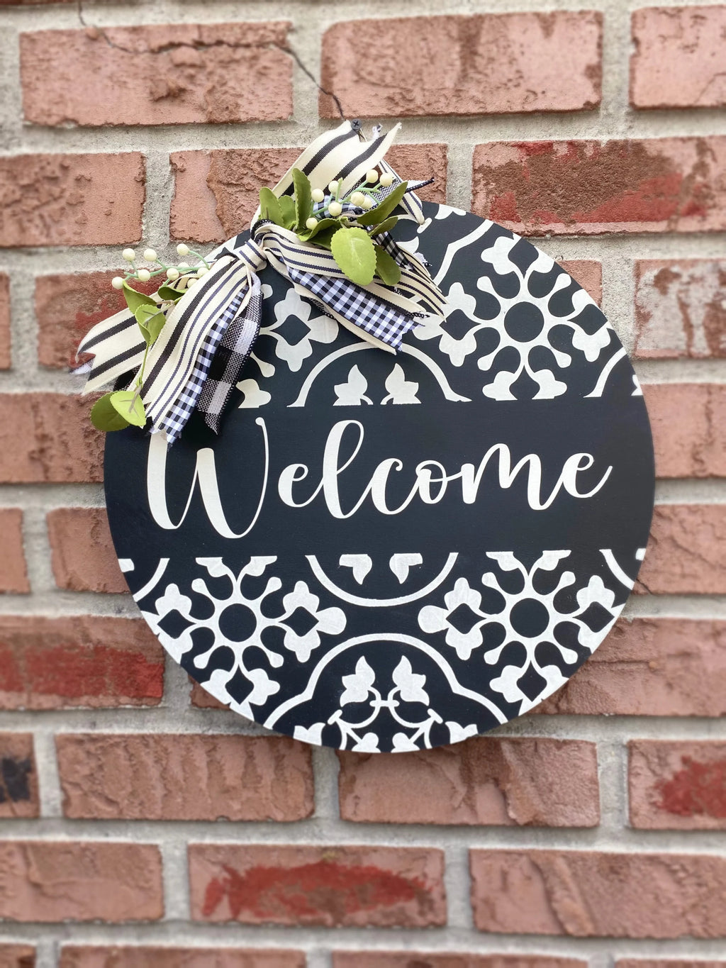 Black and white Welcome door hanger leaning on white door frame porch lifestyle shot