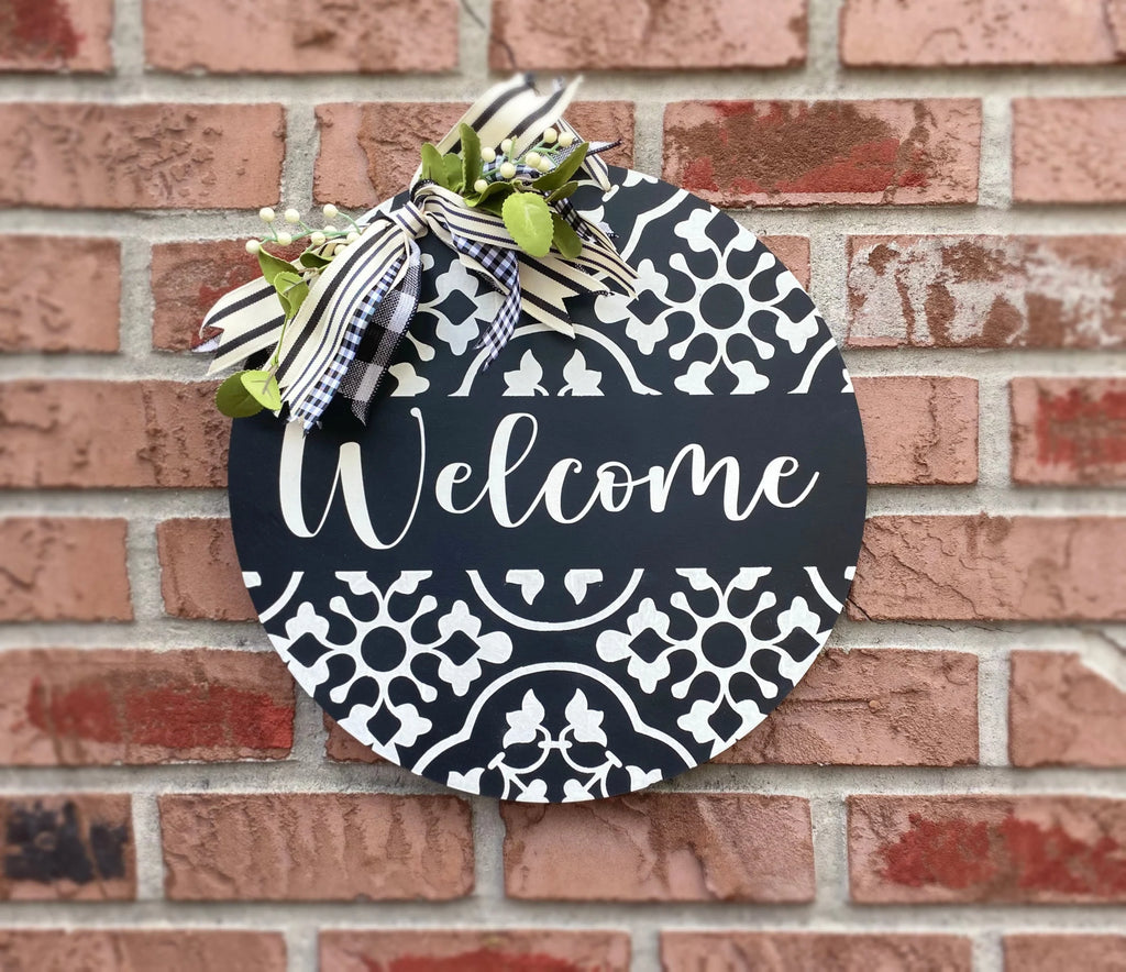 Black and white Welcome door hanger on brick wall close-up with gingham and stripe bow