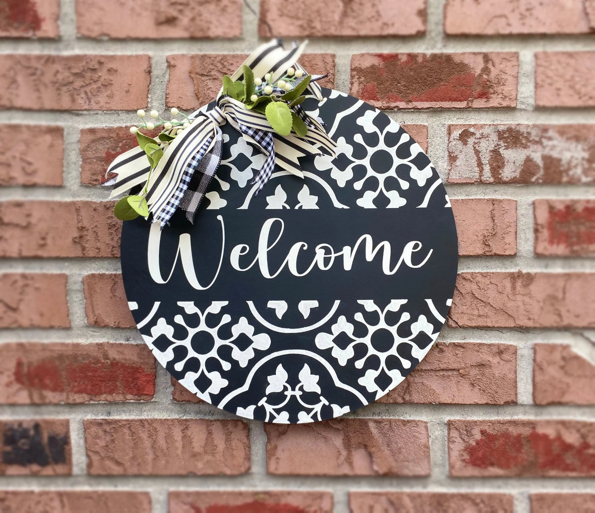 Black and white Welcome door hanger on brick wall close-up with gingham and stripe bow