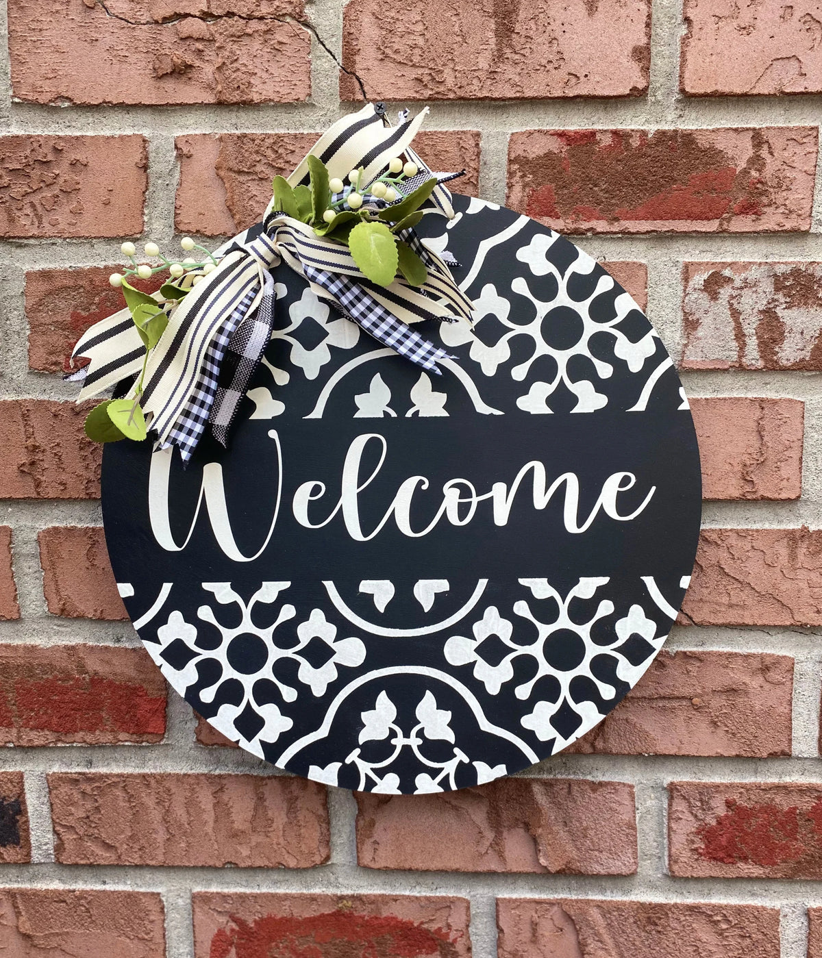 Black and white Welcome door hanger on brick wall full view with gingham bow