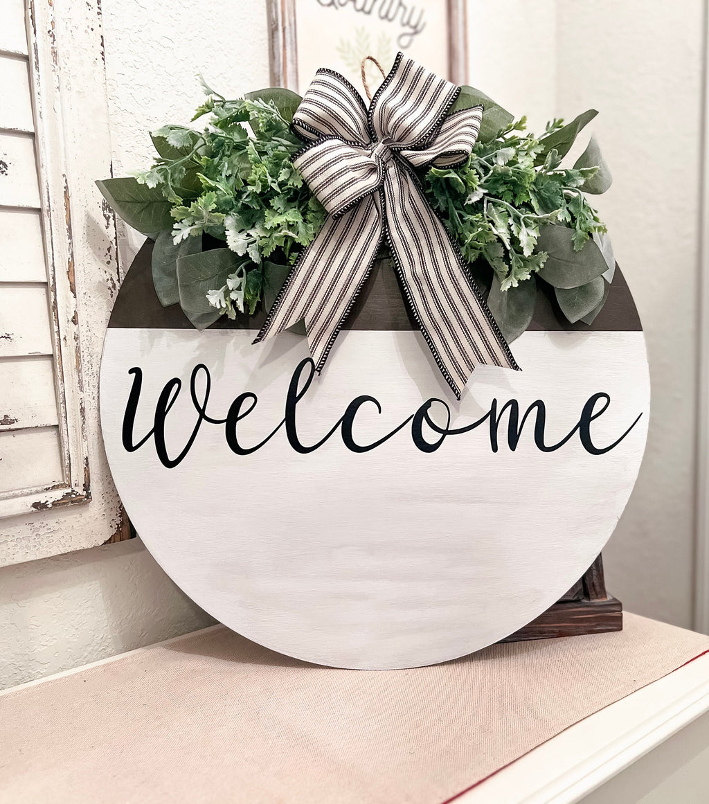 Farmhouse Welcome round door hanger with ticking stripe bow and eucalyptus greenery on white shutter shelf