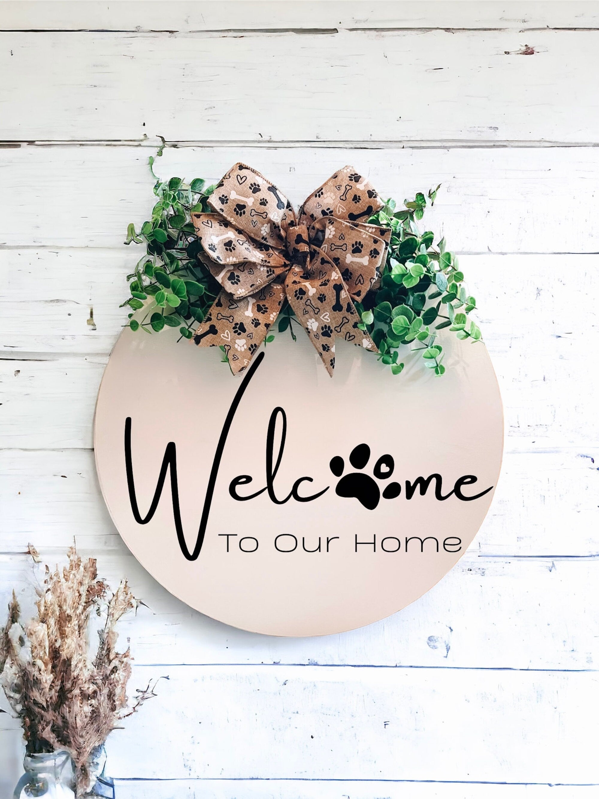 Welcome paw print door hanger on white shiplap wall with dried flowers