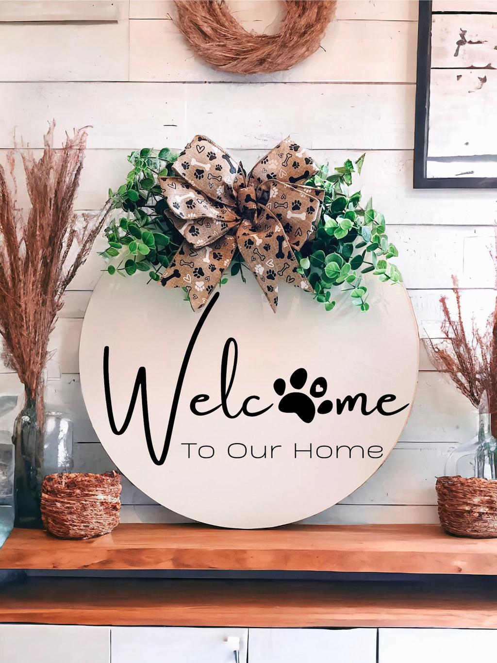 Welcome paw print door hanger on shiplap wall with dried pampas grass and woven baskets