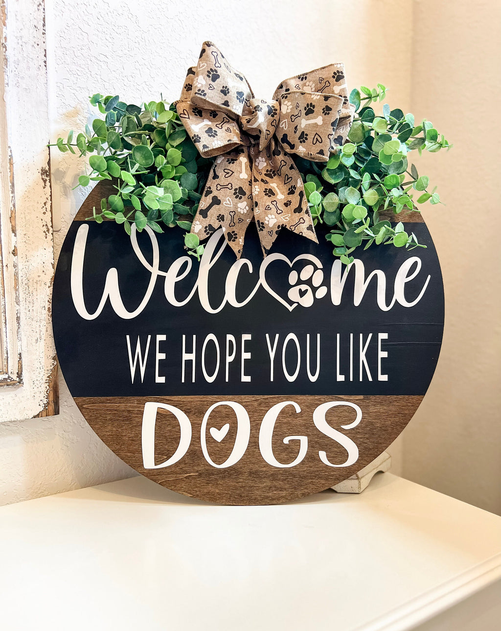 Welcome We Hope You Like Dogs two-tone round pine door hanger paw print burlap bow close up detail showing bones hearts and paw prints on tan burlap ribbon