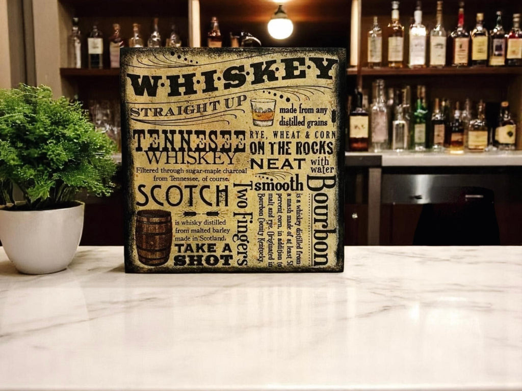 Whiskey wood block sign on wood table with green plant and copper still in background
