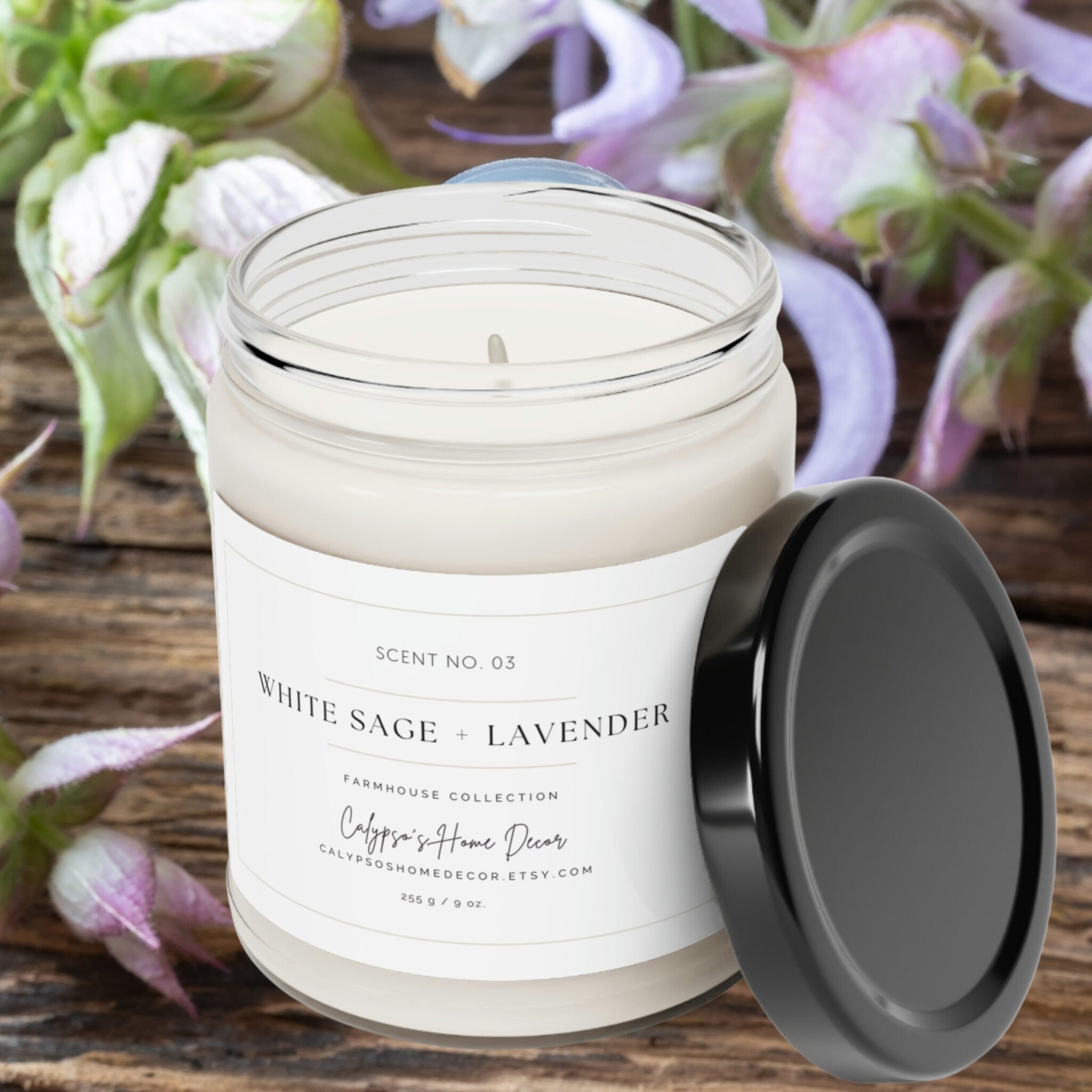 White Sage + Lavender soy candle Scent No. 03 lit in clear glass jar with black lid on dark stone surface with dramatic moody lighting
